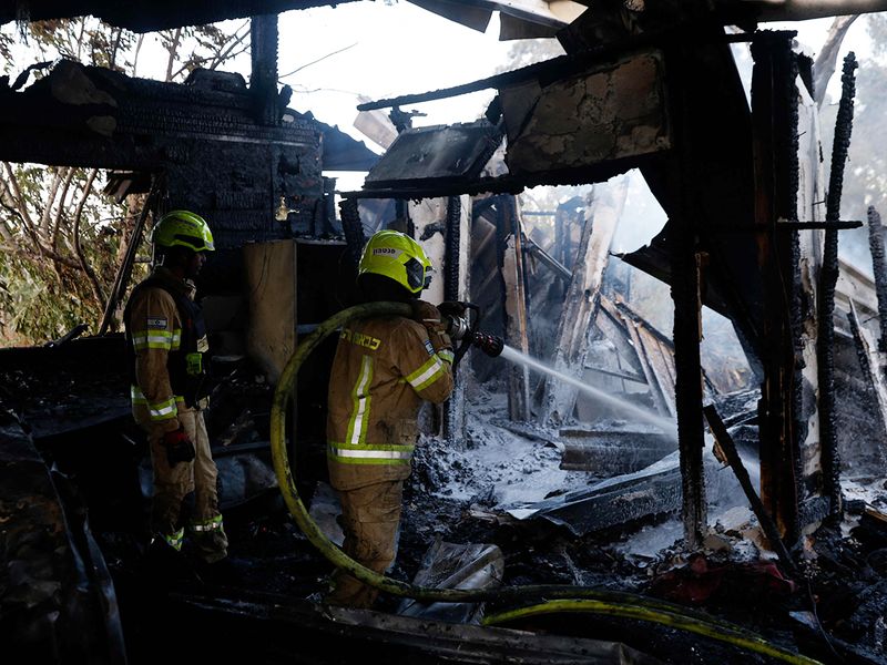 Firefighters battle the blaze at the site where rockets fired from Lebanon hit