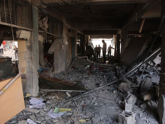 Palestinians inspect the damage at the site of an Israeli strike