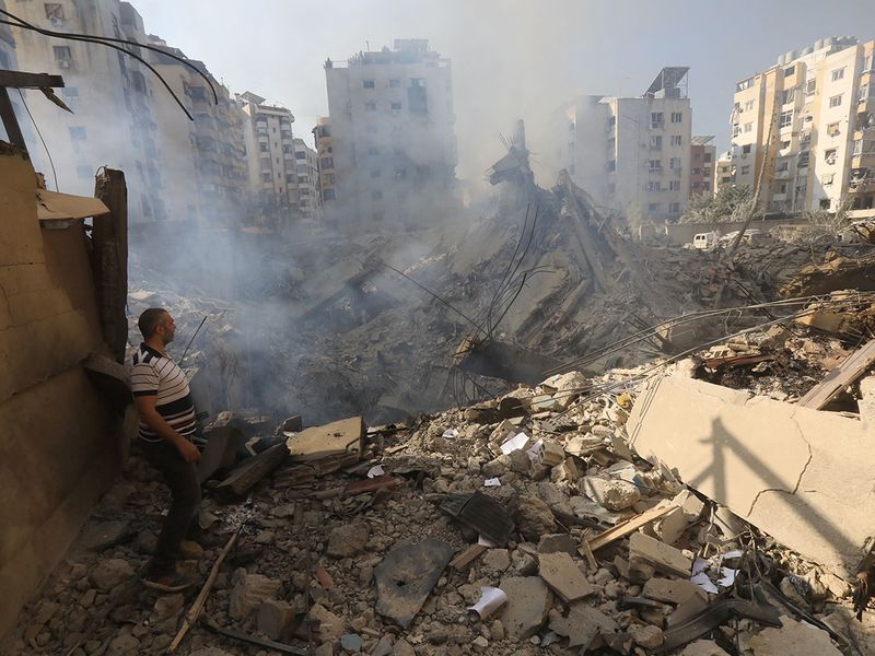 A man stands amid the rubble as people check