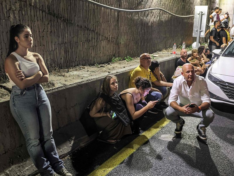 People take cover behind vehicles under a bridge along the side of a highway