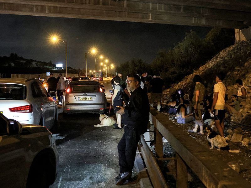 People take cover by vehicles under a bridge 