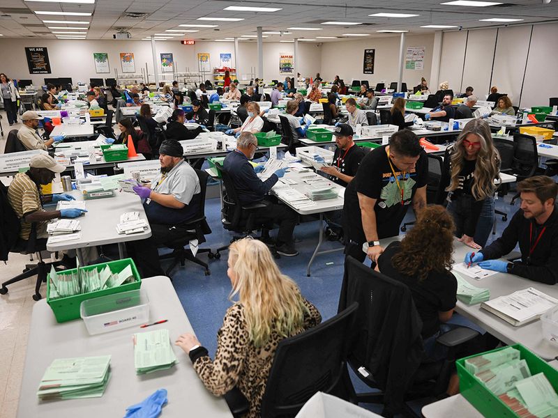 Pairs of election workers from different political parties open and inspect mail-in ballot envelopes