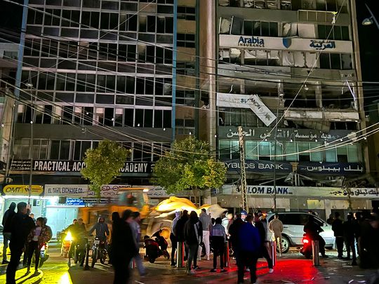 People walk at the site of an Israeli airstrike 