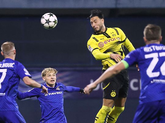 Borussia Dortmund's defender Rami Bensebaini (C)  heads the ball and scores