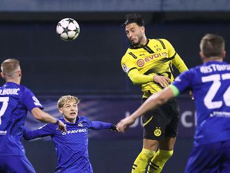 Borussia Dortmund's defender Rami Bensebaini (C)  heads the ball and scores