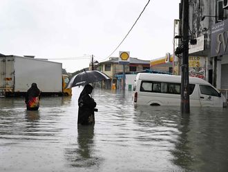 A woman looks at a submerged vehicle during heavy rain in Pasir Puteh