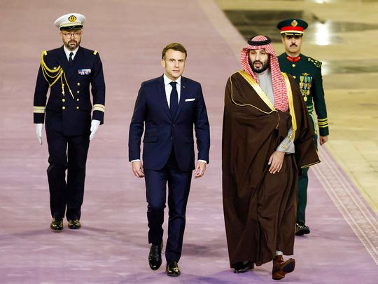 French President Emmanuel Macron (C) walks next to Saudi's Crown Prince Mohammed Bin Salman