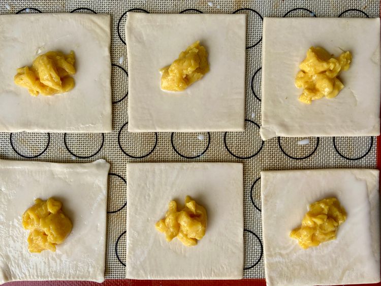 Place pastry sheets on a lined tray, spacing them apart. Brush with milk and add 1-2 teaspoons of custard in the center of each square.