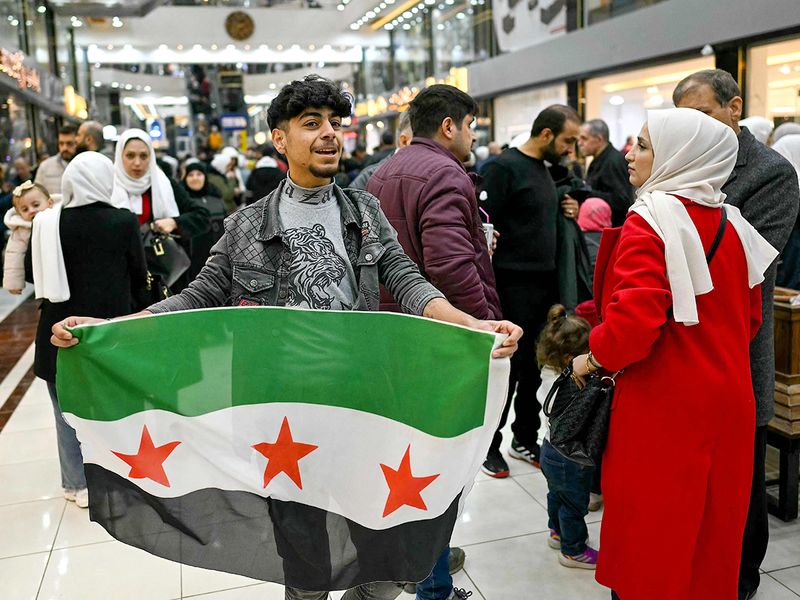 A youth holds a Syrian independence-era flag inside a shopping mall in the town of Al Dana, near Sarmada, in the northern Syrian province of Idlib. 