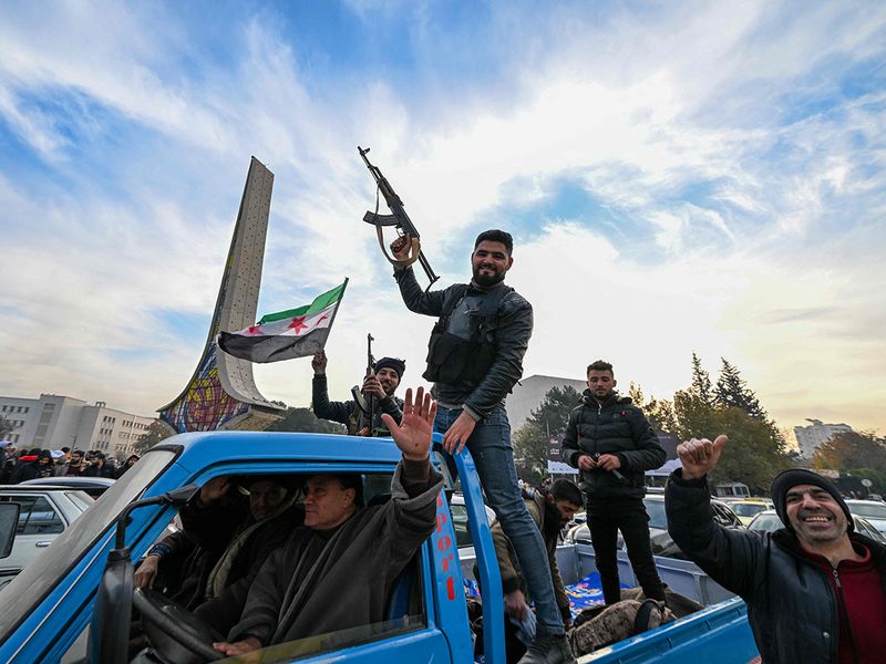 Anti-government fighters cheer from the back of a car at Umayyad Square 